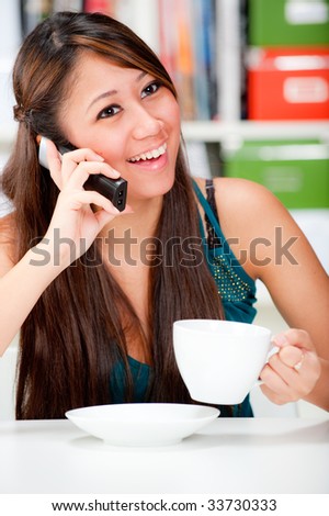 An attractive woman drinking coffee and chatting to her friend on the phone