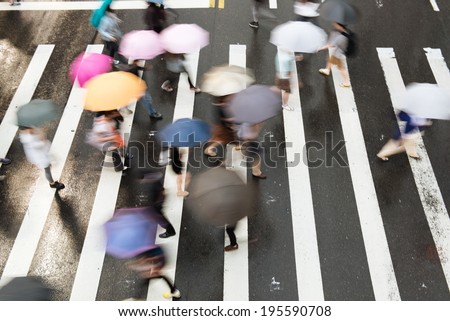 People go across the street in the rain.