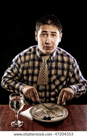 portrait of hungry broke man eating his tie after recession, isolated on black background