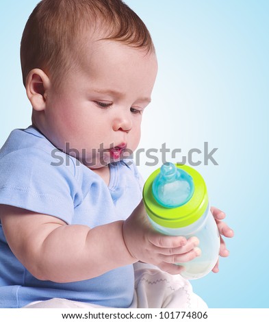Cute little baby is trying to feed himself from a bottle