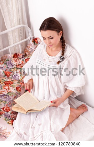 Young woman sit in a bed and read book