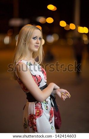 Pretty young blond girl walk through a night city street