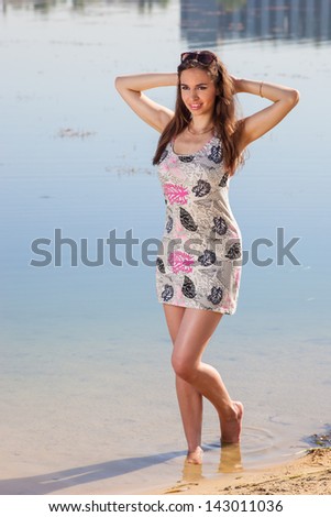 Attractive woman in the sundress on the beach of river