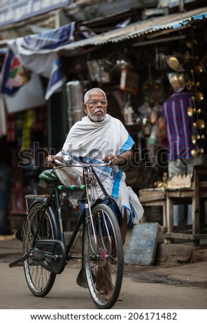 TRICHY, INDIA-FEBRUARY 14: Street of Indian city feb 14, 2013 in Trichy, India. Old man with a bike on the street of indian town