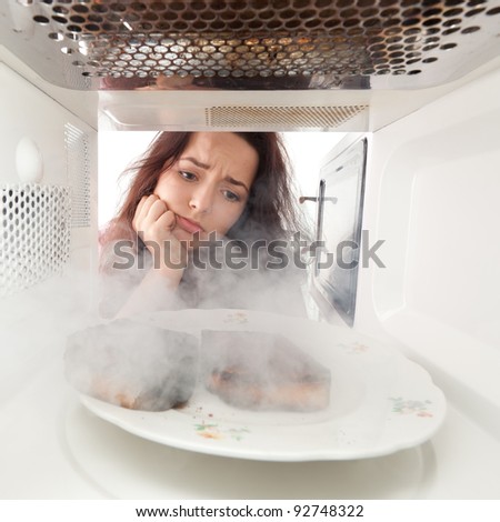 Sad young girl burn toasts in a microwave