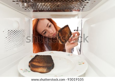 Girl look to a burned toasts in microwave