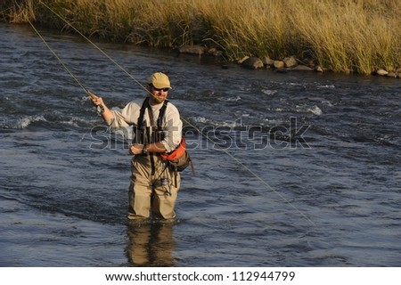 Fly-fisherman casting to trout on the Umzimkulu river,Underberg,Southern drakensberg, Kwazulu natal, South Africa.  The Umzimkulu lies at the heartland of South Africa\'s trout fishing region