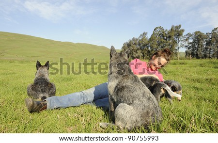 australian cattle dogs and woman relaxing in field
