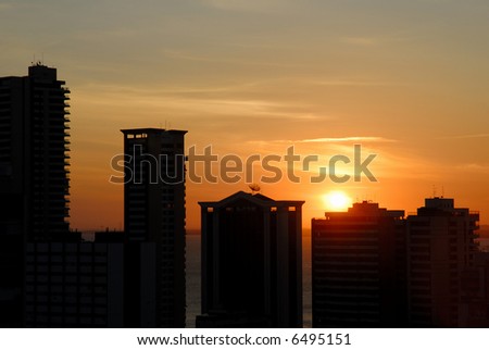 Sun down behind the buildings in the city .