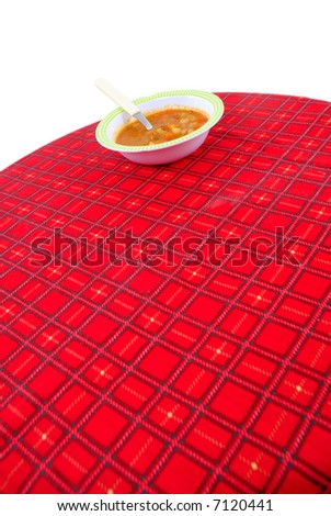 Vegetables Soup on the Red Tablecloth with black square lines .