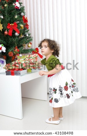 Cute Girl opening gift in the Christmas tree .