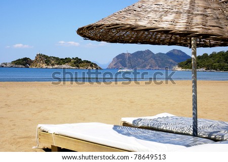 Beautiful seascape with yacht and mountains, beach and umbrella