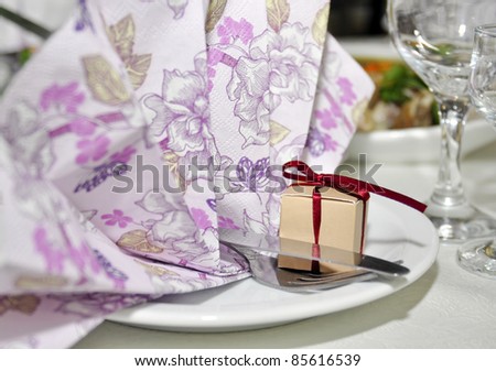 Napkin, surprise box, knife, fork, and glasses on wedding table