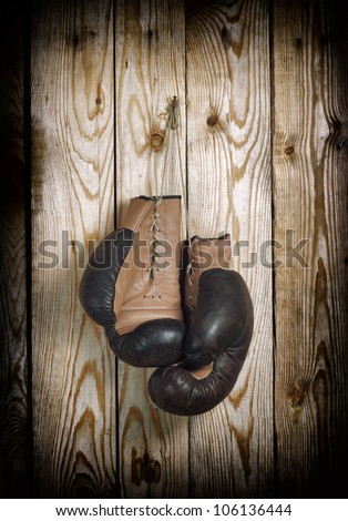 Brown old boxing gloves with a lace over old wooden wall