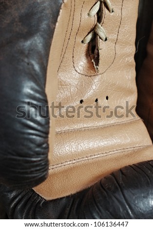 Brown old boxing gloves with a lace over old wooden wall
