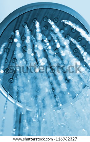 Photograph of a shower head water drops with bokhe sparkles and streams of water. Blue toned.