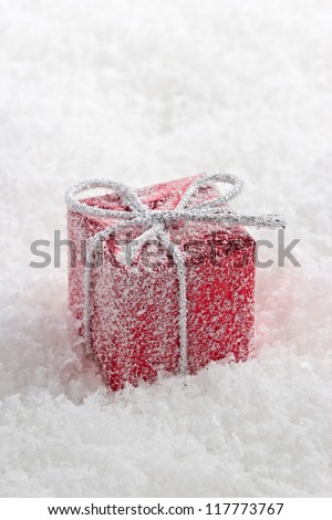 Abstract red gift box with white frost in snow.
