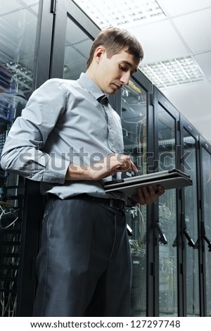 The engineer stand in data center near telecommunication equipment with tablet PC