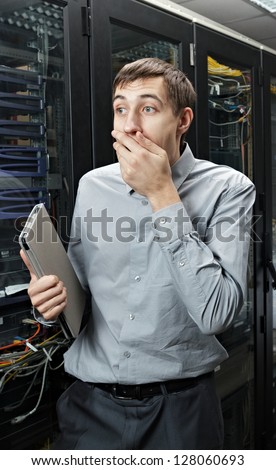The surprised engineer stand in data center near telecommunication equipment with tablet PC.