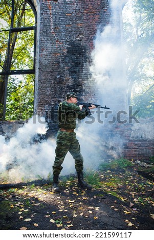 Soldier or militiaman in camouflage with assault rifle fighting in ruins