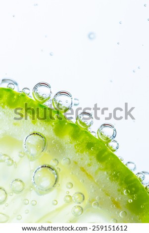 Slice of lime in water with bubbles