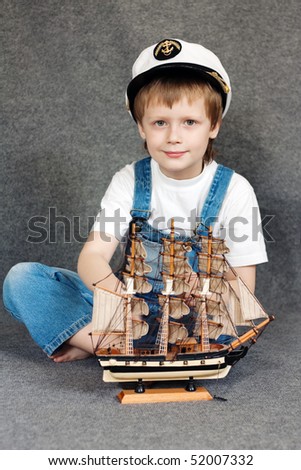 Portrait of the cute dreaming child with the model ship.