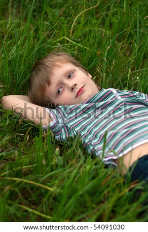 The little boy has laid down on a grass to dream