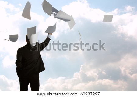 The young man, the businessman, in a dark business suit throws a pile of documents upwards, for a back. The beginning of new life.