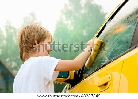 Little boy washing car. Summer. Sunset