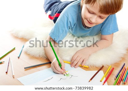 Cute dreaming child lies and draw on soft sheep fur isolated over white background.
