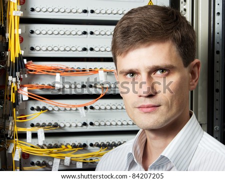 The engineer in a data processing center of ISP Internet Service Provider stand near fiber optic cross box.