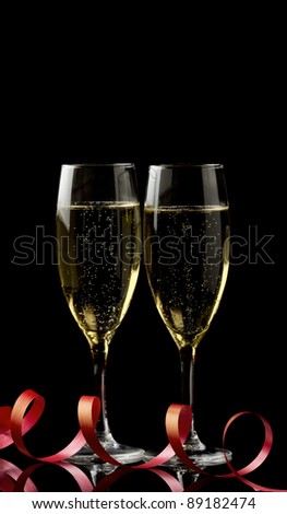Two glasses with white wine over black background with red ribbon. Copy-space.