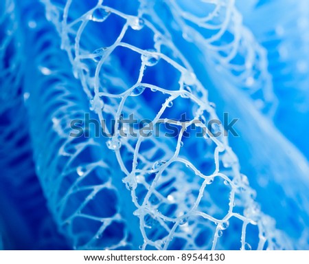 Abstract macro photo of massage blue bath sponge with water drops.