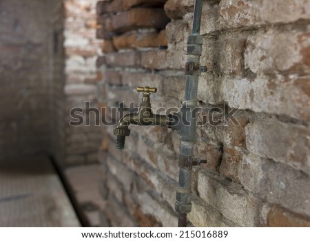 Room with old brick wall and copper water tap
