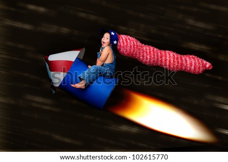 Patriotic Blast Off:  adorable young boy in a stars and stripes hat clings to a rocket as it speeds through the night sky