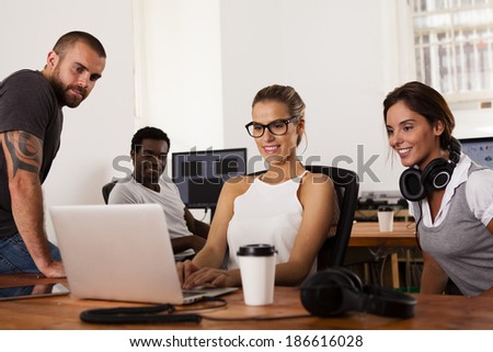 Team of young entrepreneurs looking at a laptop computer in a tech startup office