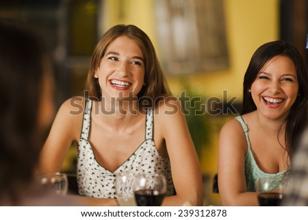 Two young women laughting with friends in a restaurant