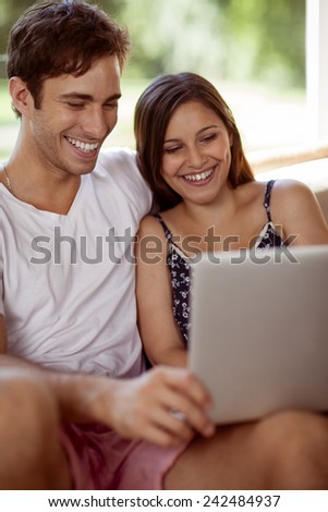 Young couple relaxing and smiling at home with a laptop computer