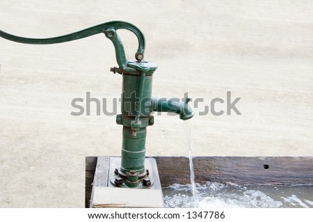 An old fashioned water pump above a drinking trough.