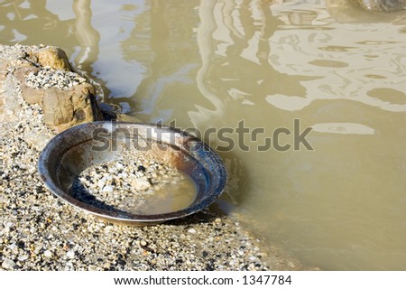 A prospector\'s pan left by the river. This is the pan that is used to search for alluvial gold in the stones of the river.