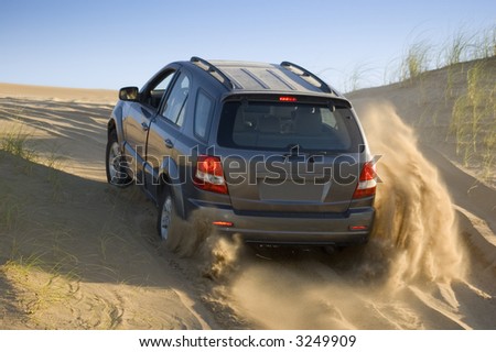 A four-wheel-drive drives through the   sand dunes.