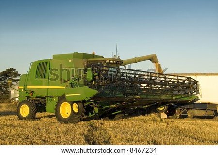 A modern combine harvester emptying grain into a truck