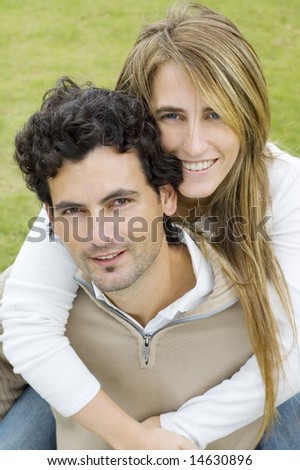 A young couple playing affectionately in a garden, both looking at the camera