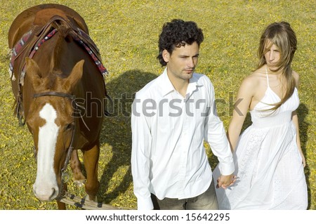 A young couple walking with their horse