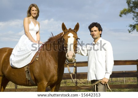 A young couple with their horse - the woman riding and the man leading