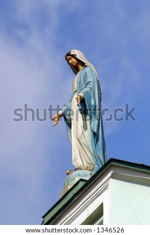 Wooden sculpture of virgin Maria on blue sky