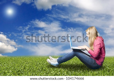 teenager girl in a meadow with her laptop chatting online