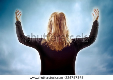 woman with open arms in front of a mystical sky