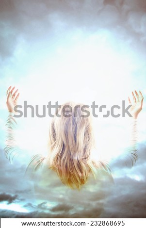 woman with open arms in front of a divine light in the sky