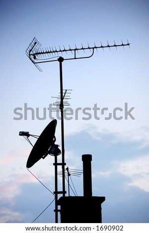 antennas and satellite dish in silhouette over a blue sunset sky